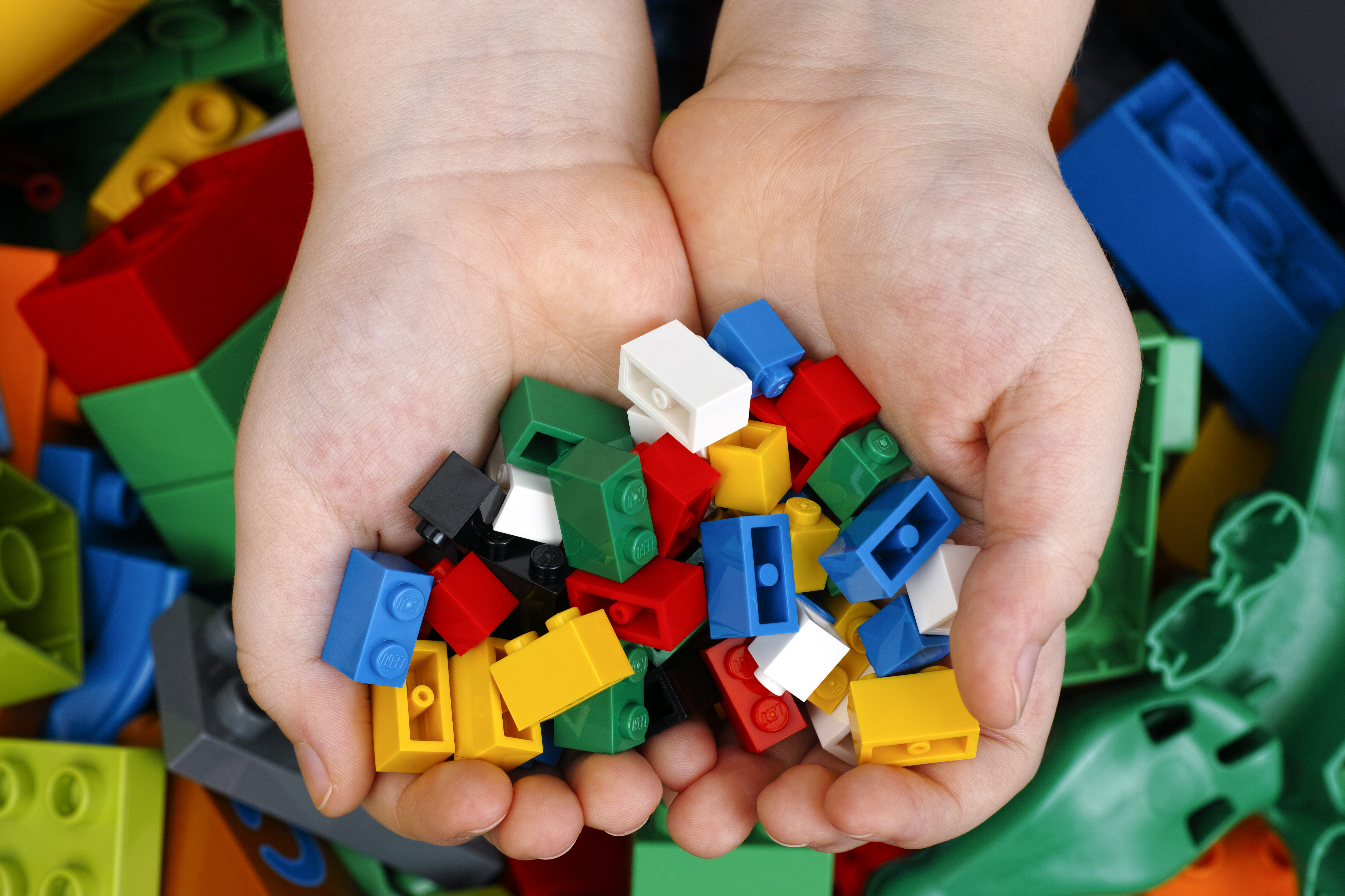 Photo of a child's hands full of LEGOs.