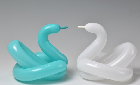 Two balloon animal swans (one teal and one white) facing each other.