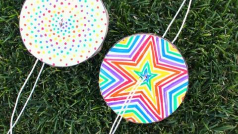 Image of two colorfully designed paper spinners on grass.