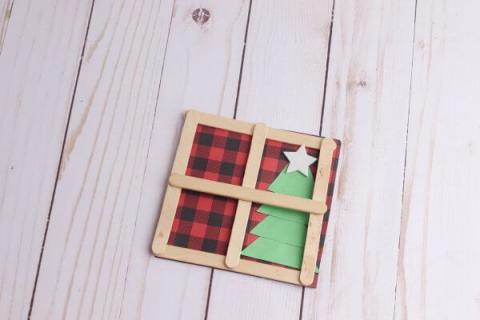 Image of a popsicle stick "window frame" with a view of a Christmas tree