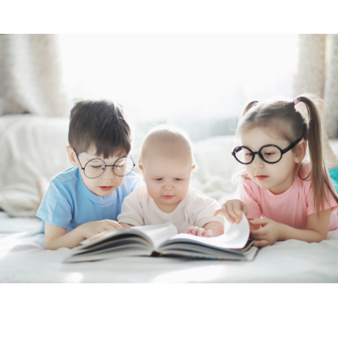 A boy, girl, and baby looking at a book together.
