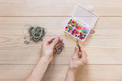 Hands adding beads to a small bracelet.