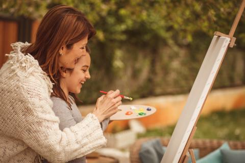 Image of a mother painting a canvas with her daughter. 