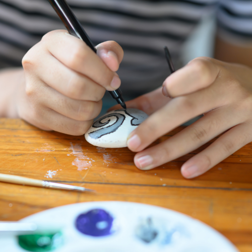 Person painting a rock.